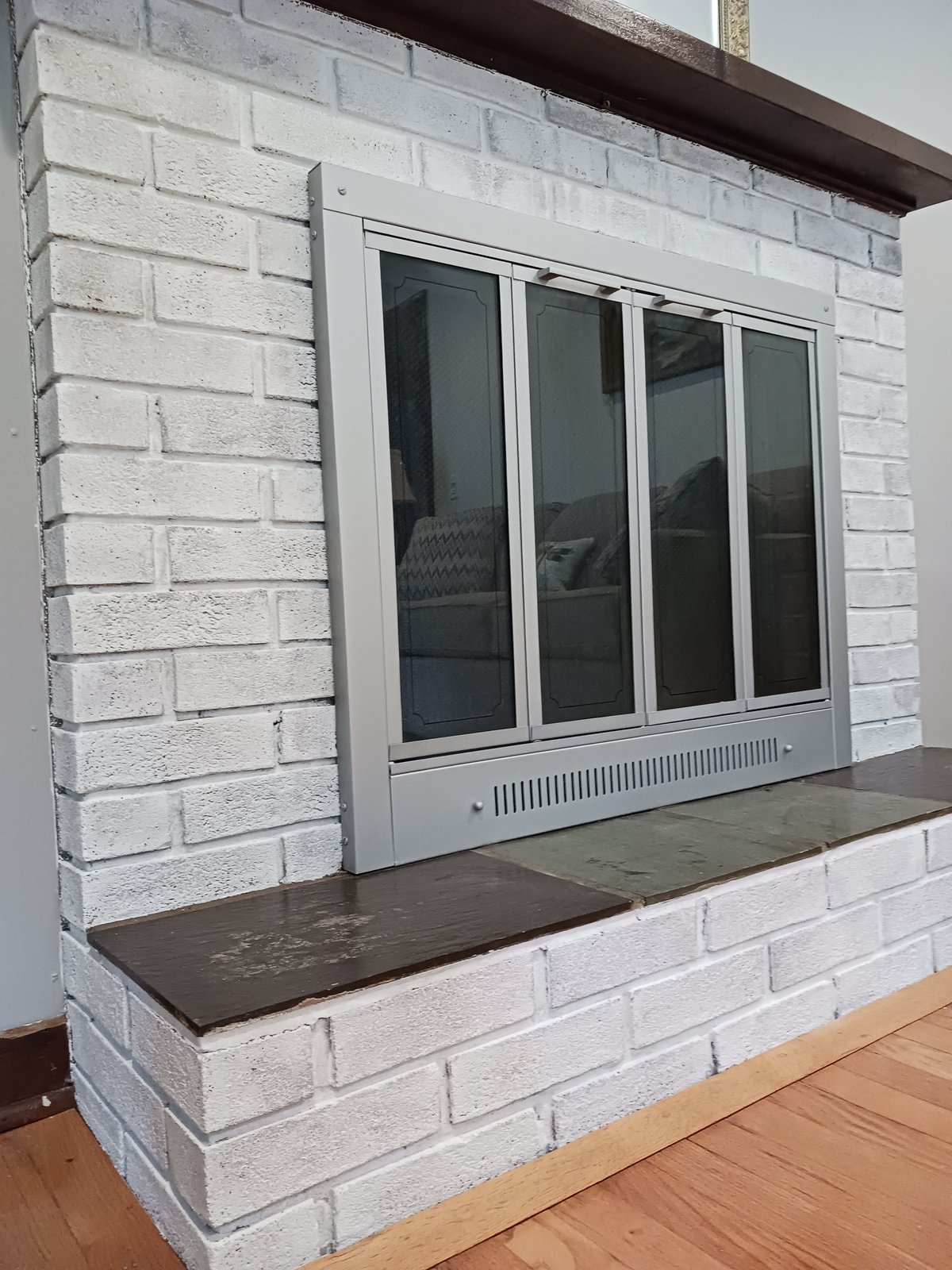Whitewashed brick fireplace with dark wood mantel